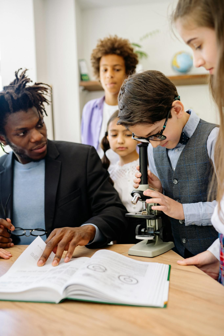 Students and teacher in a science class using a microscope for learning.