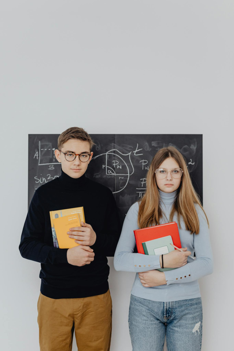 Two students hold books with a blackboard background, reflecting a classroom setting.
